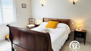 Una camera da letto con un letto di legno, un cuscino giallo, due comodini con lampade e una finestra con vista.