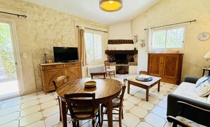 Een gezellige woonkamer met een open haard, houten meubels en een televisietoestel.