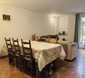 Un coin repas avec une table et des chaises, une kitchenette et une porte-fenêtre coulissante donnant sur une terrasse extérieure.