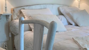 Un dormitorio con cama, almohadas, una silla y lámparas de noche.