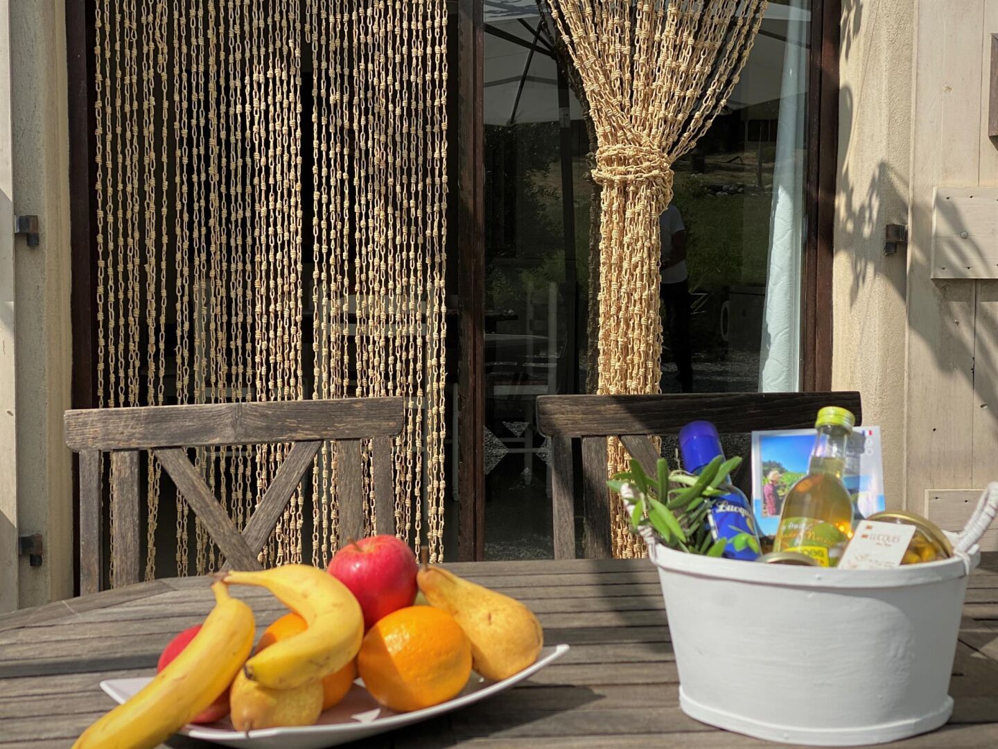 Una mesa de madera con un plato de fruta y un cubo blanco con botellas y un marco de fotos.