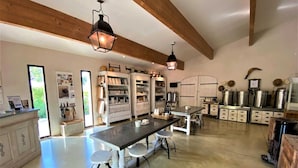 Una cocina amplia con una mesa larga y taburetes, vigas de madera en el techo, y varios electrodomésticos y armarios de almacenamiento.