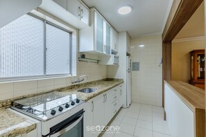 Una cucina con mobili bianchi, un piano di lavoro in granito, un fornello a gas e un forno a microonde.