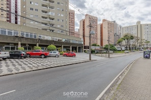 Un espace de stationnement avec plusieurs voitures, un immeuble à étages et un passage piétonnier.