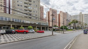 Un estacionamiento con varios coches, un edificio de varios pisos y una acera.
