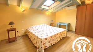 A bedroom with a bed, a small table, a lamp, a wardrobe, and a skylight. - La Cave de Jean - GARDIE (GARDIE)