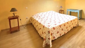 Un dormitorio con cama, una mesita, lámpara, armario y tragaluz.