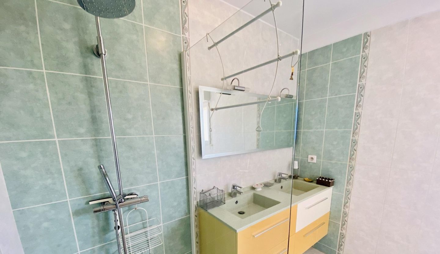 Ein Badezimmer mit Dusche, zwei Waschbecken, einem Spiegel und einem Handtuchhalter.
