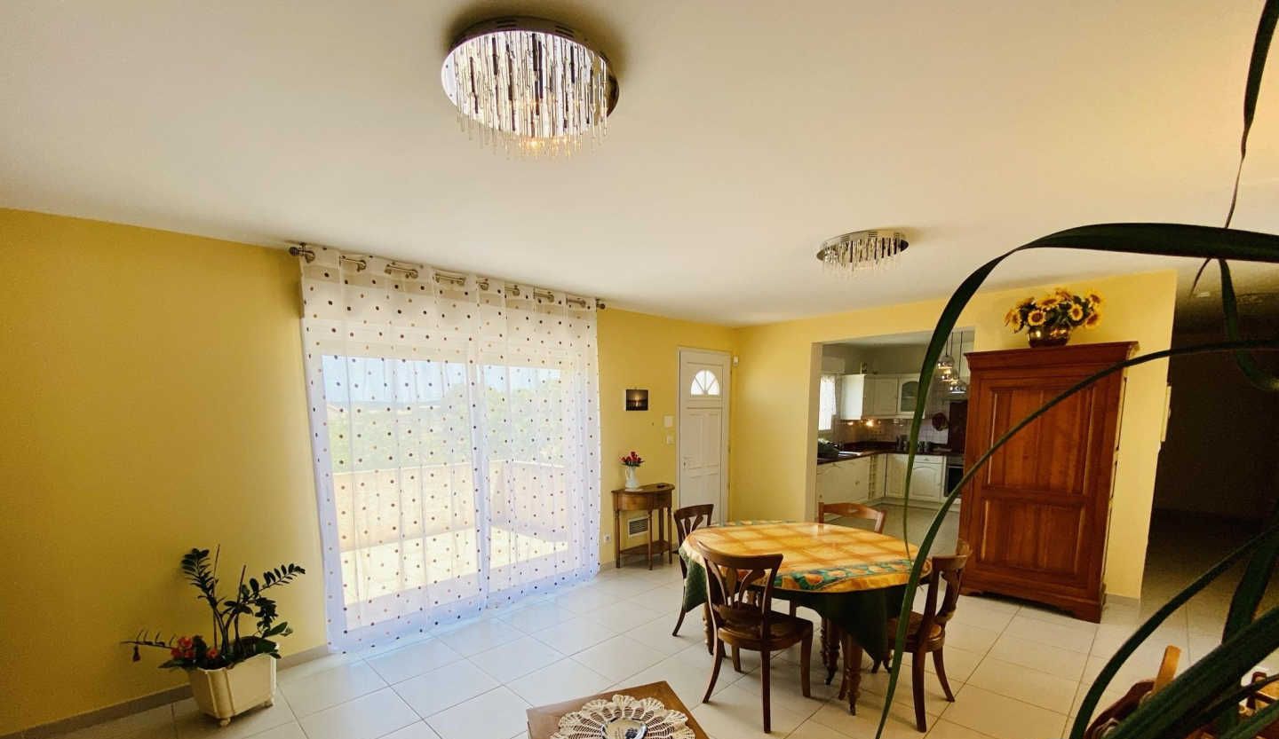 A dining area with a table and chairs, a chandelier, and a view into the kitchen.