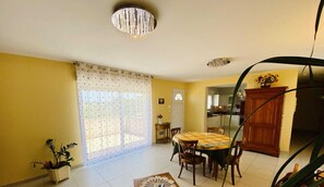 A dining area with a table and chairs, a chandelier, and a view into the kitchen.