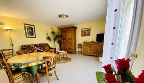 A dining area with a wooden table and chairs, a sofa, a cabinet, and a television.