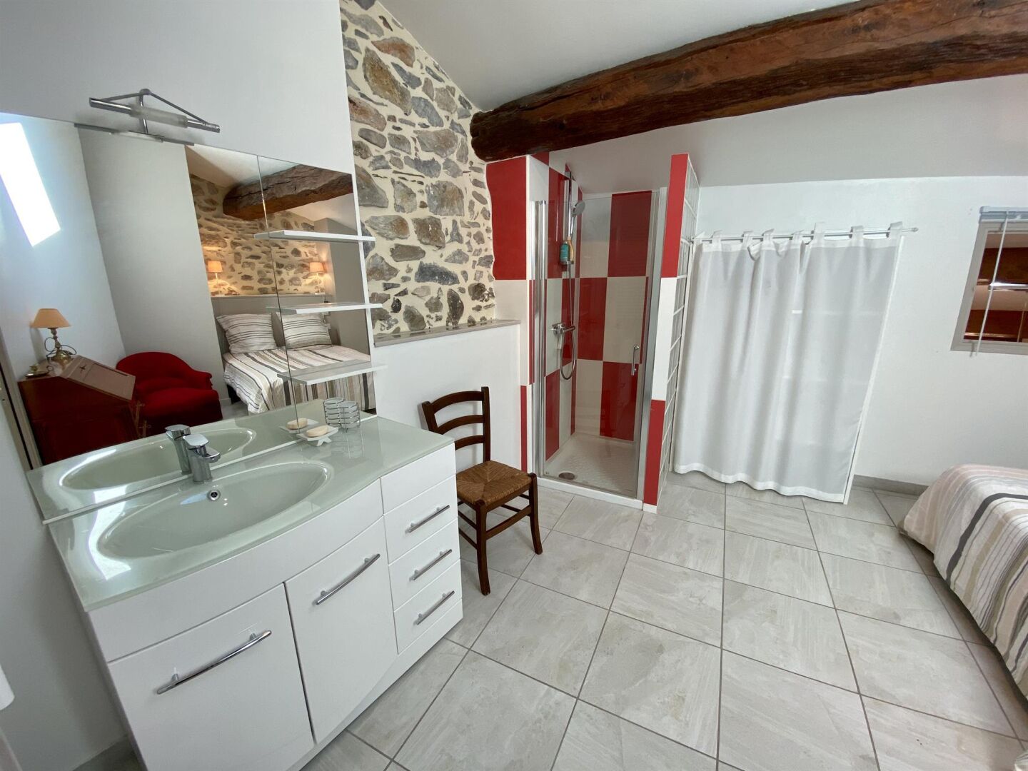 A bathroom with a glass sink, a shower, and a red and white tiled shower enclosure.