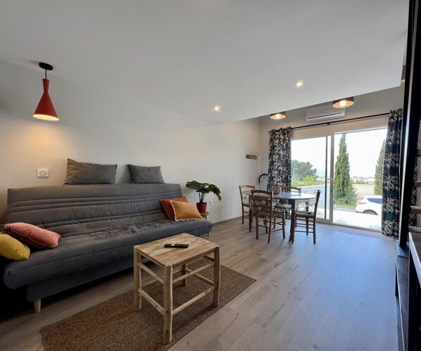 Una sala moderna con un sofá gris, una mesa de centro de madera y un comedor con mesa y sillas.