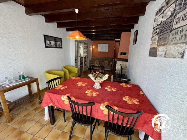 A dining area with a red tablecloth, two black chairs, a wooden table, and a yellow chair.
