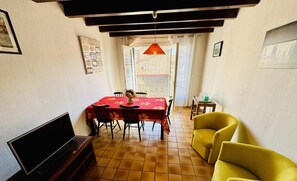 Un coin repas avec une nappe rouge, des chaises et un téléviseur.