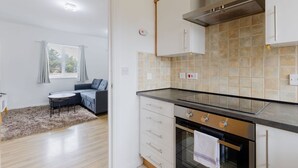 Une cuisine moderne équipée d’un four encastré, d’une cuisinière à gaz et d’une hotte en acier inoxydable. On y trouve également un coin repas avec une table et des chaises, ainsi qu’une fenêtre avec des rideaux.
