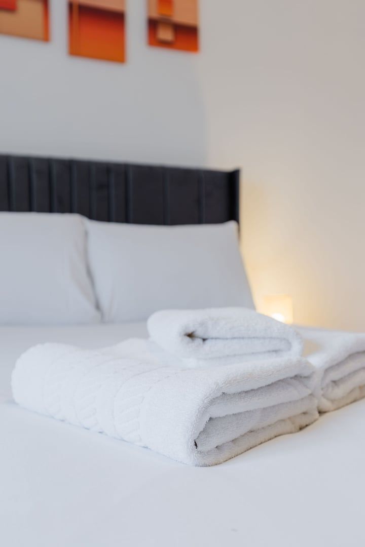 Un lit bien fait, avec du linge de lit blanc et des serviettes pliées.