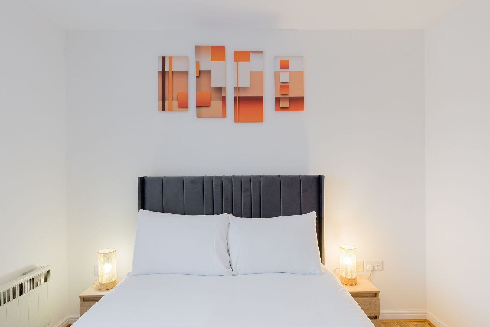A neatly made bed with white linens, a dark headboard, and two bedside lamps on wooden nightstands.