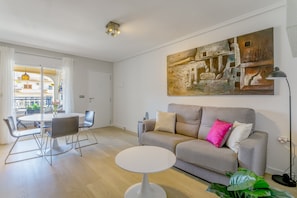 A modern living room with a sofa, a round table, and a dining area with chairs.