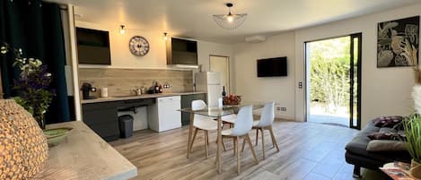 Un apartamento moderno con cocina, comedor y sala de estar. Cuenta con un ventanal grande, un televisor de pantalla plana y una planta decorativa.