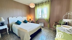 A hotel room with a bed, a bedside table with a lamp, a chair, and a window with curtains.