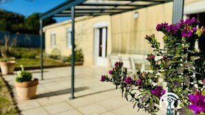 A covered outdoor area with a building in the background, potted plants, and a logo with the text "Gites de France".
