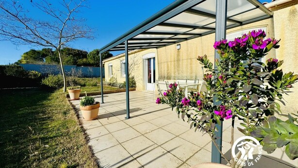 A covered patio area with potted plants and a view of a building with a door.