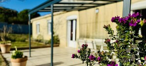 Un espacio al aire libre cubierto con un edificio al fondo, plantas en macetas y un logotipo con el texto "Gites de France".