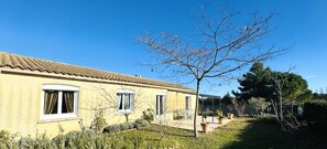 Un edificio amarillo con tejado de tejas, un porche cubierto y un árbol en primer plano.