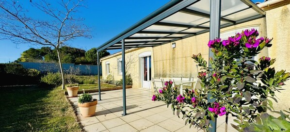 Un patio cubierto con plantas en macetas y vistas a un edificio con una puerta.