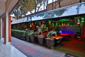 Un ristorante all'aperto con pareti in mattoni, piante in vaso e una struttura in vetro.