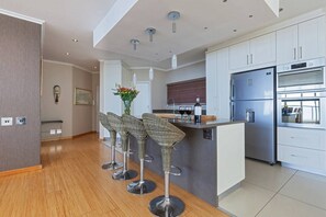 A modern kitchen with a central island, stainless steel appliances, and a bar area with high stools.