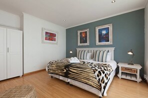 A bedroom with a bed, a nightstand, a lamp, and two framed pictures on the wall.