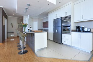 A modern kitchen with white cabinets, stainless steel appliances, and a central island with bar stools.