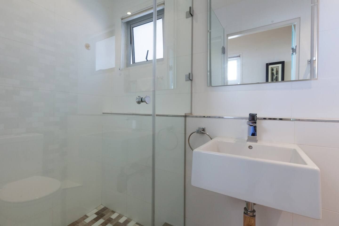 A modern bathroom with a glass shower enclosure, a white sink, and a large mirror.