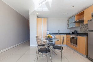 Een moderne keuken met een eetgedeelte, met een ronde tafel, vier stoelen en een inbouwoven.