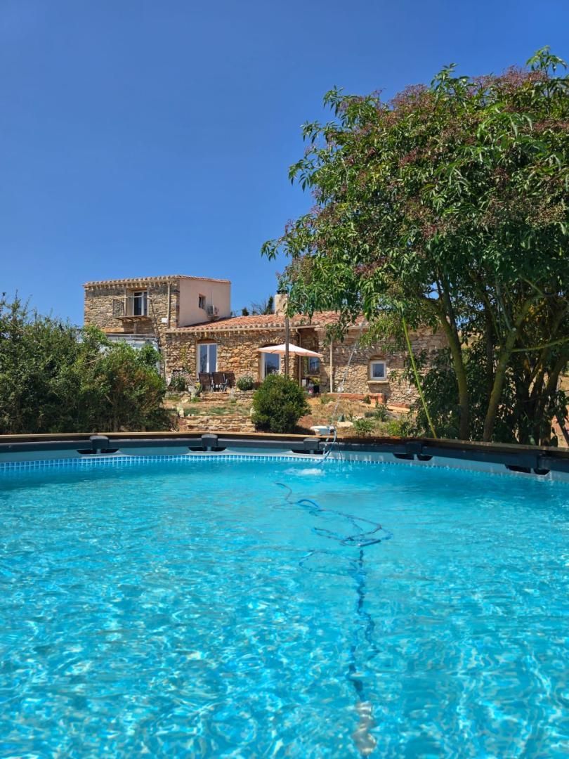 Una piscina azul y cristalina con un edificio de piedra al fondo.