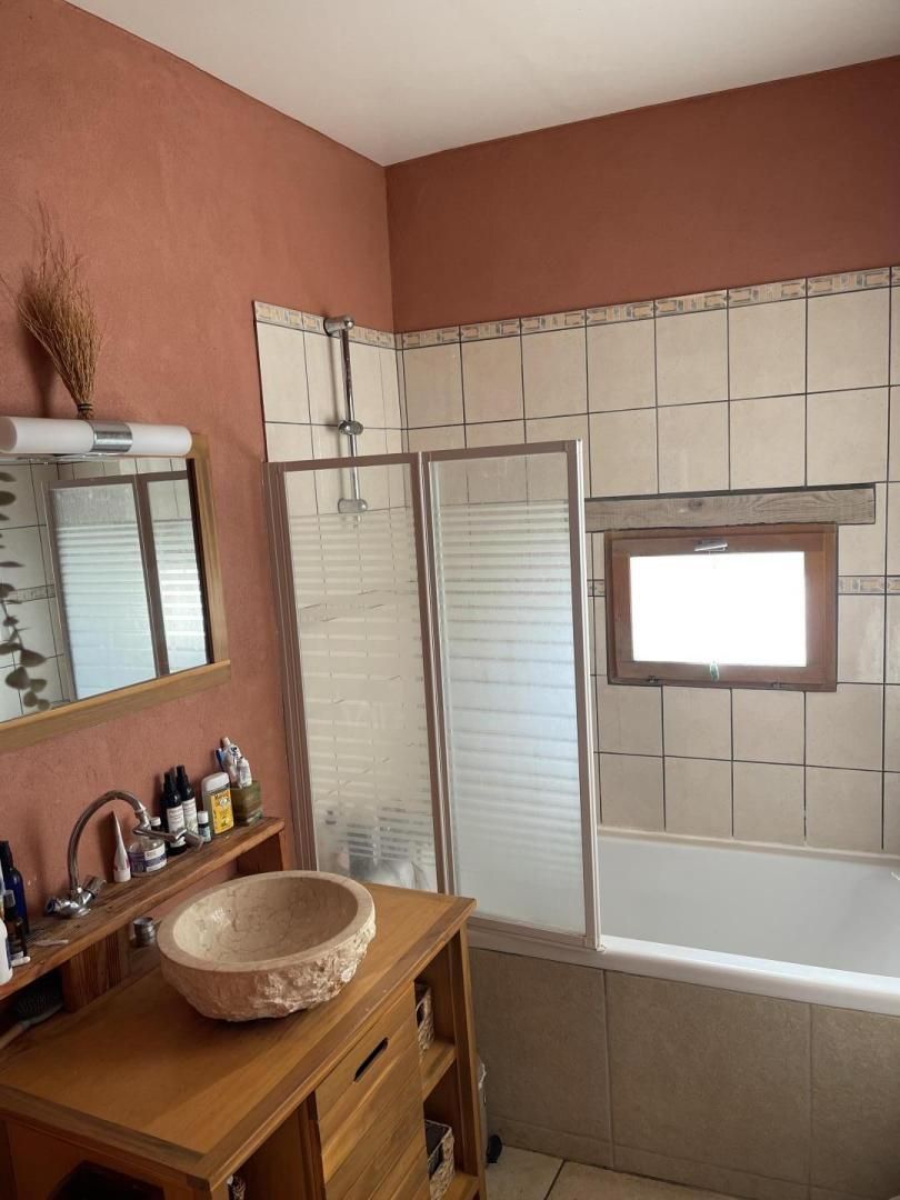 A bathroom with a wooden vanity, a large mirror, a sink, and a bathtub.