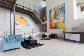 Un amplio vestíbulo con una escalera, una recepción y arte abstracto en las paredes.