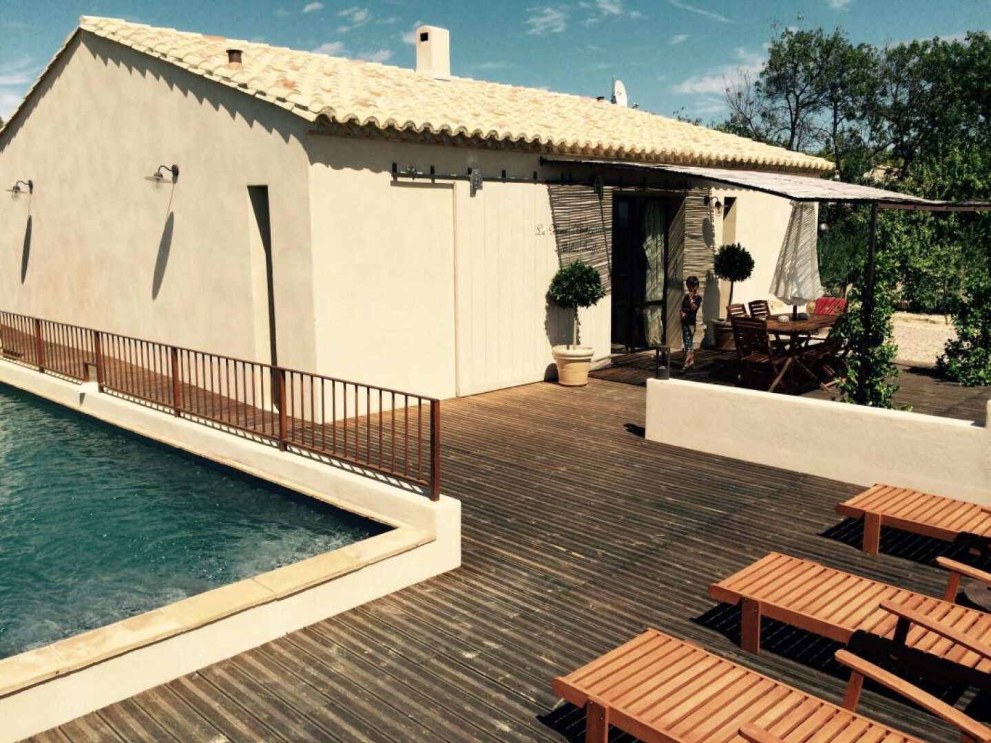 A poolside area with a wooden deck, a pool, and outdoor seating.