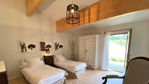 Una camera da letto con due letti, soffitto in legno, un armadio e una sedia.