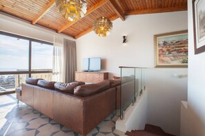 A modern living room with a sofa, television, and a painting on the wall.