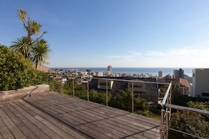 A wooden deck with a view of a cityscape and the sea.