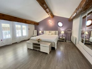 Ein Schlafzimmer mit einem großen Bett, einem Nachttisch, einer Lampe und einem Spiegel.