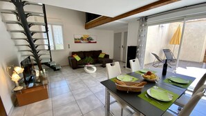 Ein Essbereich mit Tisch für vier Personen, einer Couch und einer Treppe.