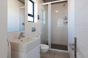 Un bagno moderno con doccia vetro, lavandino bianco e WC.