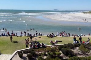 A beach with people, grassy areas, and a clear sky.