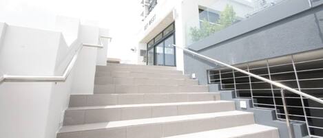 Un conjunto de escaleras exteriores que conducen a un edificio de diseño moderno, con barandilla de metal y fachada de vidrio.
