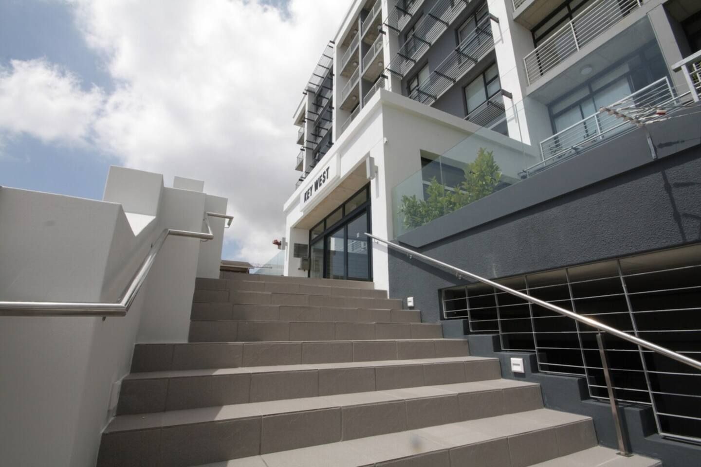 Un bâtiment moderne avec un escalier menant à l’entrée située au rez-de-chaussée.