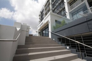 A modern building with a staircase leading to a ground floor entrance.